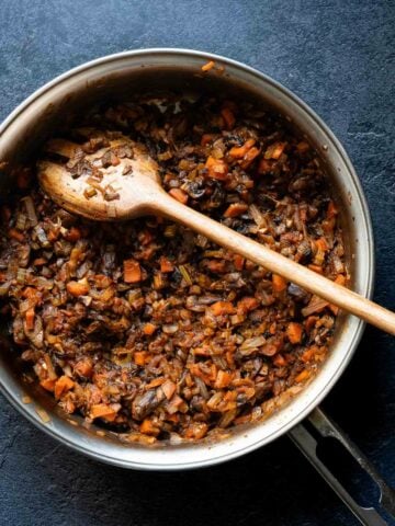 Mixed vegetables and lentils being stirred in a pot to create the pie's filling.