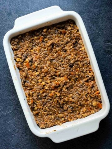 Lentil and vegetable filling in a white baking dish, before topping with mashed potatoes.