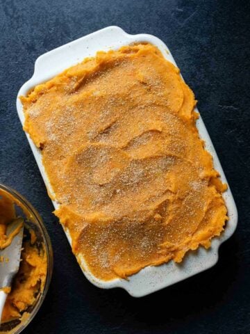 Vegan shepherd's pie with a smooth layer of mashed sweet potatoes in a white baking dish.