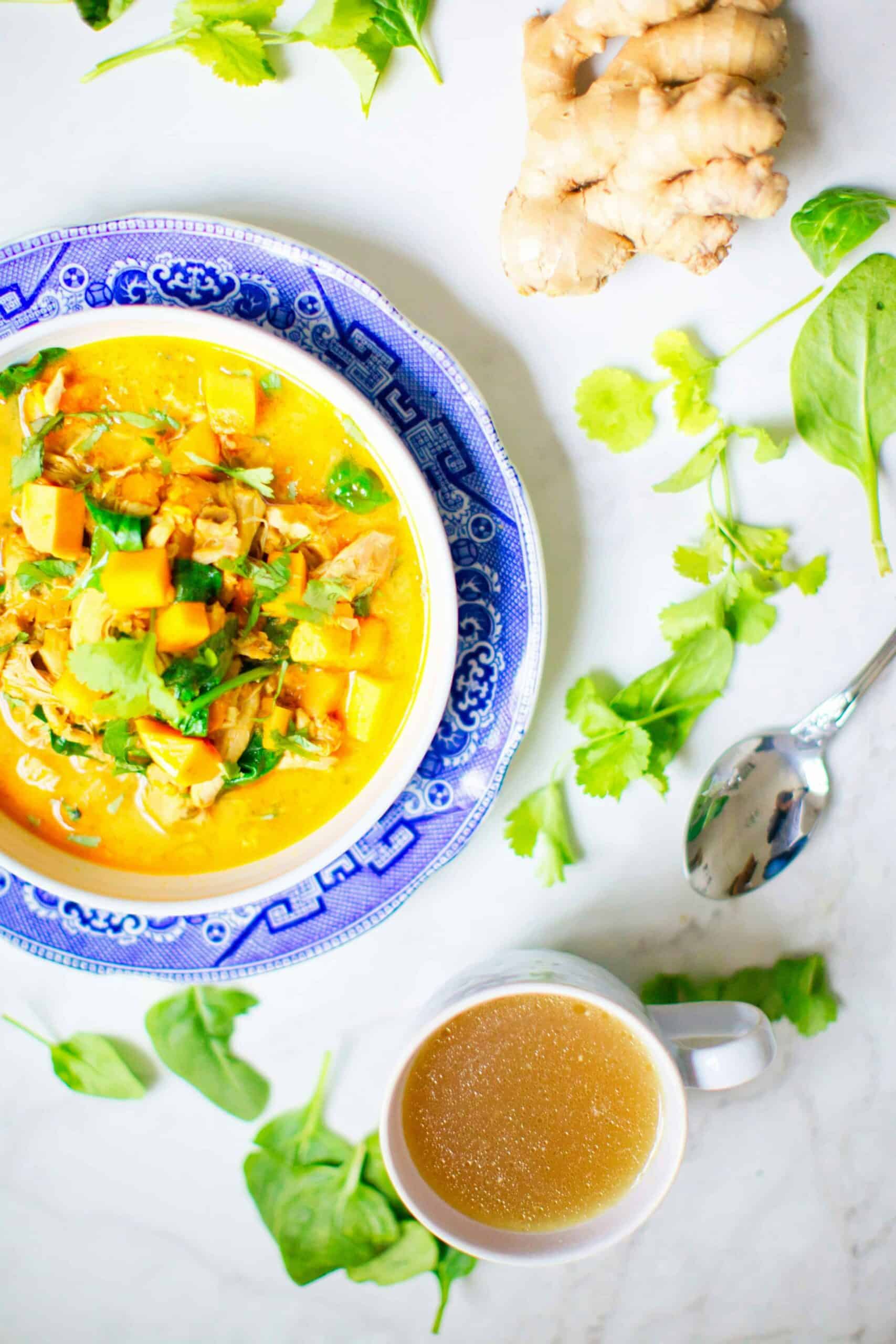 comforting close-up bowl of vegan soup with a cup of hot tea and ginger table setting